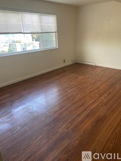 A room with wooden flooring and a window with blinds.