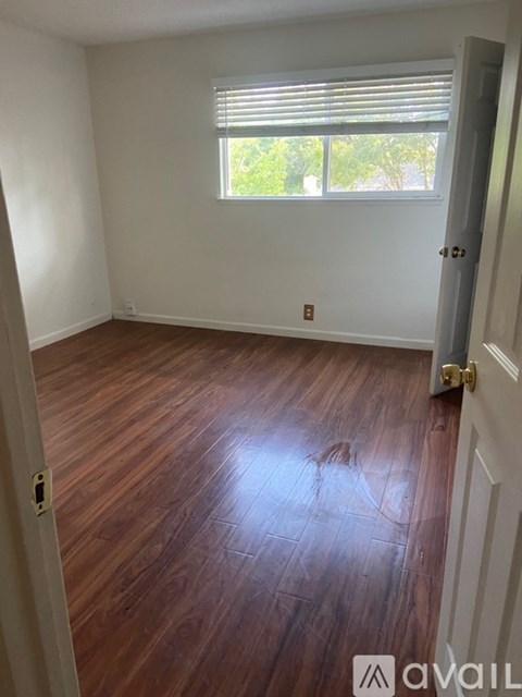A room with wooden flooring and a window with blinds.