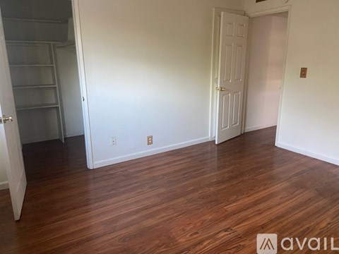 A room with wood flooring and two doors, one of which is open.
