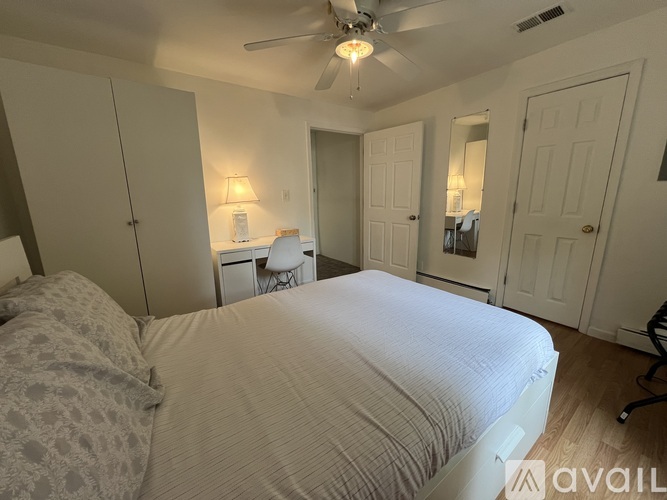 A bedroom with a large bed and a ceiling fan.