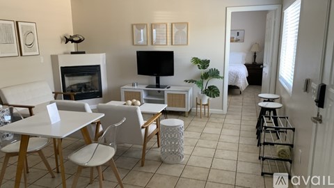 A living room with a white table and chairs, a fireplace, and a TV on the wall.