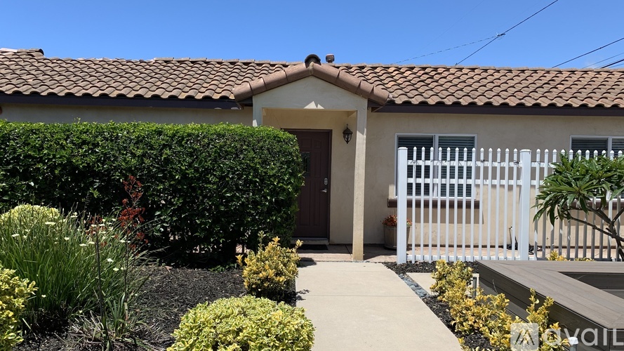 A house with a white fence and a brown roof.