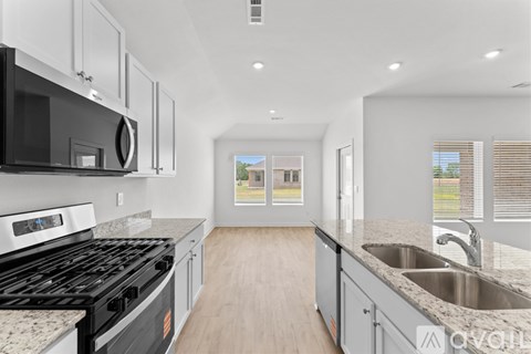 A modern kitchen with a black stove top oven and a granite counter top.