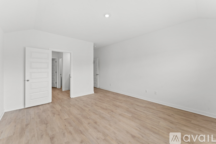 A spacious room with wooden flooring and white walls.