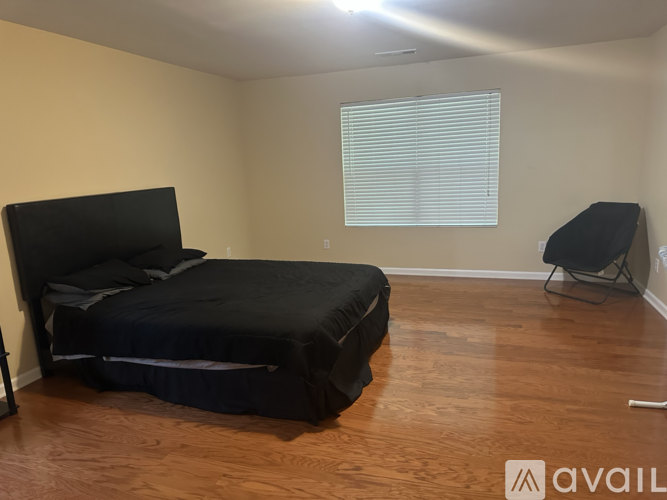 A bedroom with a black bed and a chair.