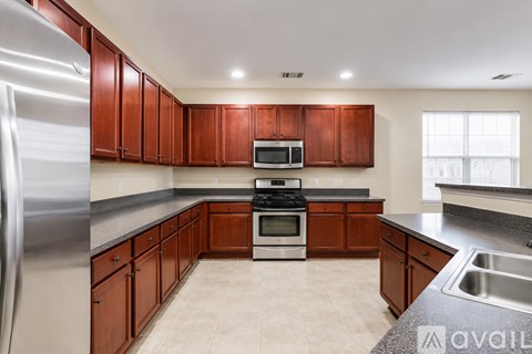 A kitchen with brown cabinets and a stainless steel refrigerator.