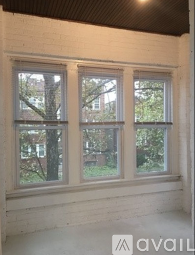 A white room with a window and a view of trees outside.