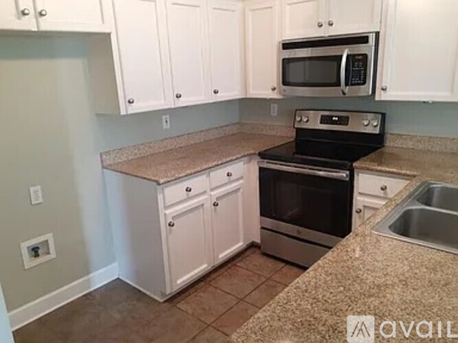 A kitchen with white cabinets and a granite countertop.