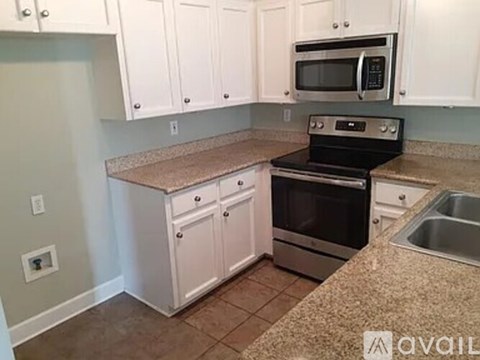A kitchen with white cabinets and a granite countertop.