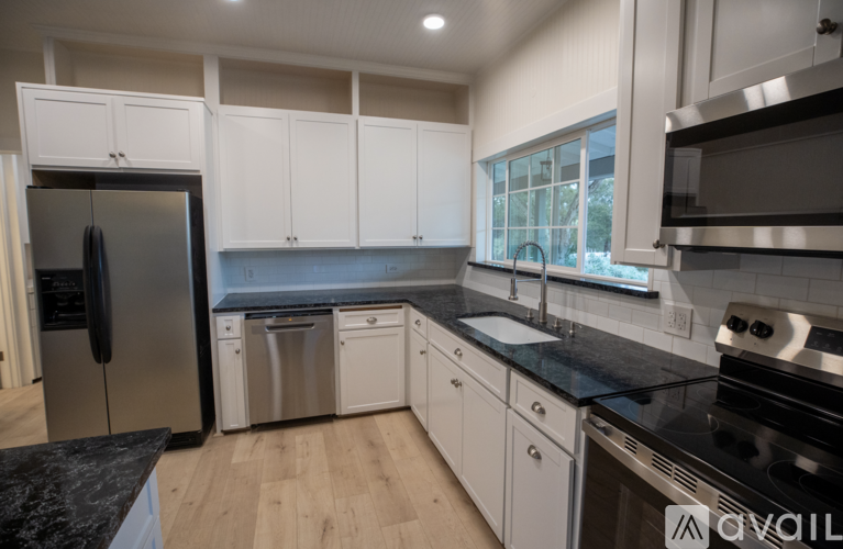 A kitchen with white cabinets and black countertops.