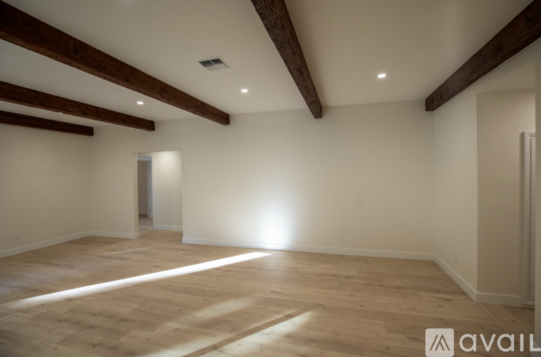A spacious room with wooden beams on the ceiling and light streaming in from a window.