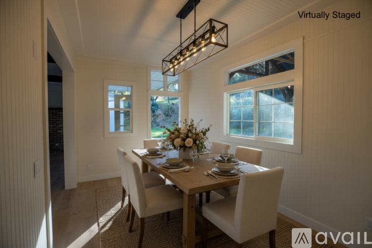 A dining room with a wooden table set for two with a chandelier hanging above.