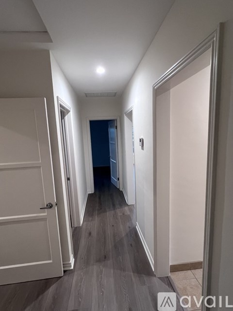A long hallway with a door on the left and a light on the ceiling.