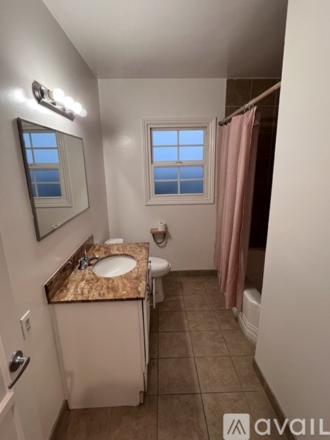 A bathroom with a sink, mirror, toilet, and a window.