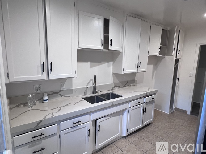 A kitchen with white cabinets and a marble countertop.