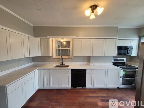A kitchen with white cabinets and a black dishwasher.