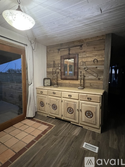 A wooden dresser with a mirror above it and a clock on the wall.