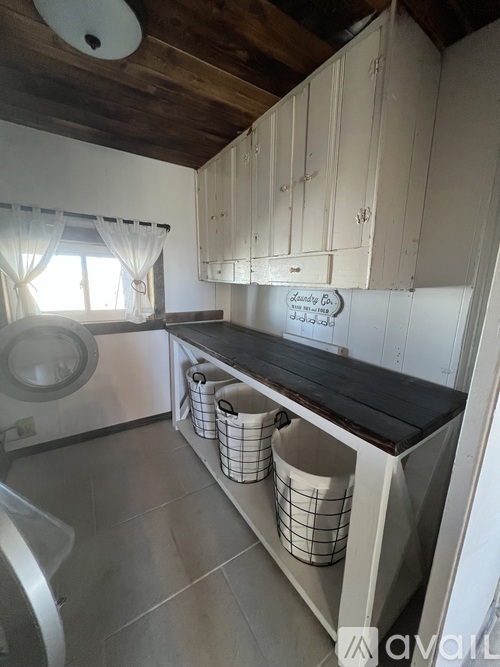 A kitchen with white cabinets and a wooden ceiling.
