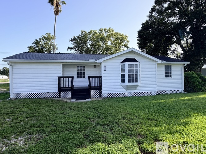 A white house with a black roof and a porch.