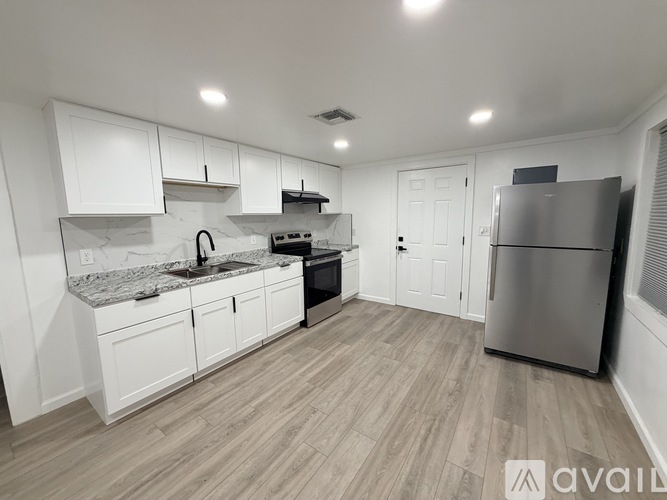 A kitchen with white cabinets and a marble countertop.
