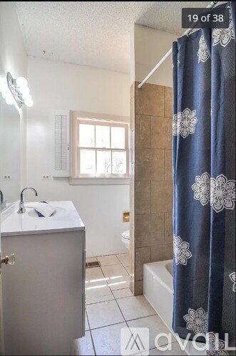 A bathroom with a white sink and a blue shower curtain.