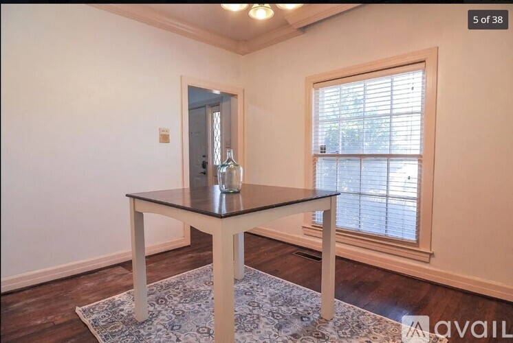 A table with a glass on it sits in a room with a window.