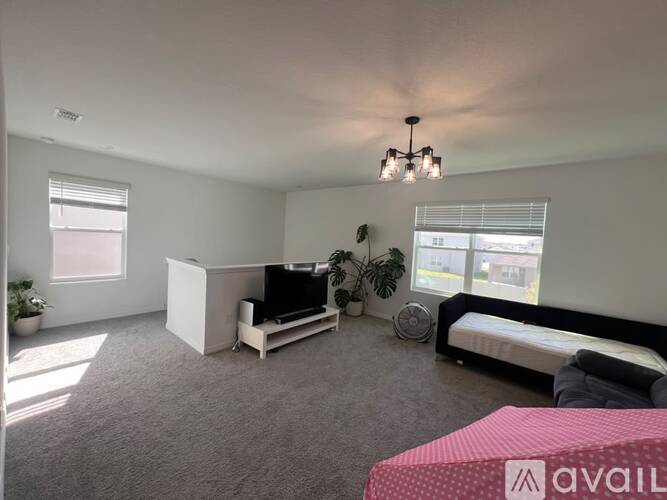 A living room with a couch, a television, and a window with blinds.