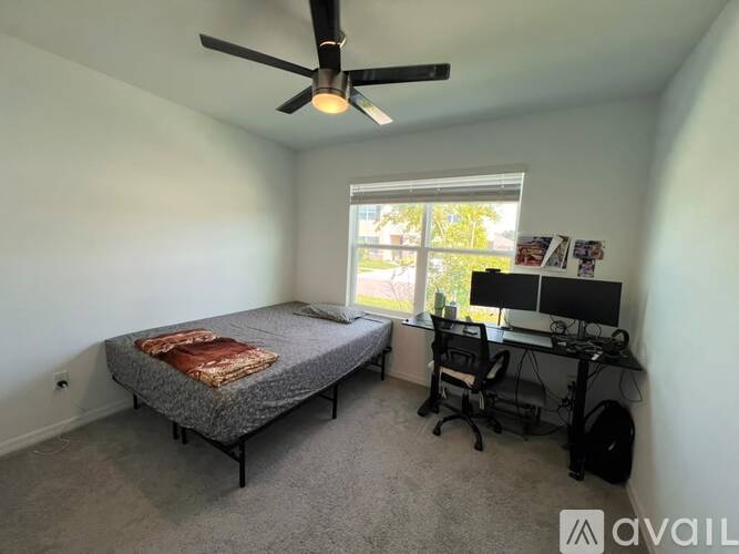 A bedroom with a bed, desk, and ceiling fan.