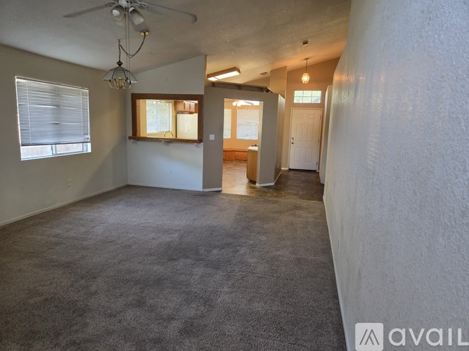 A spacious room with a carpeted floor and a ceiling fan.