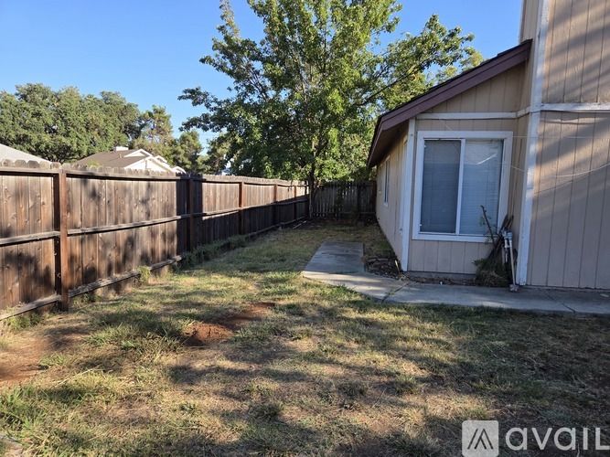 A backyard with a wooden fence and a house.