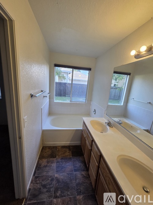 A bathroom with a tub, sink, and mirror.