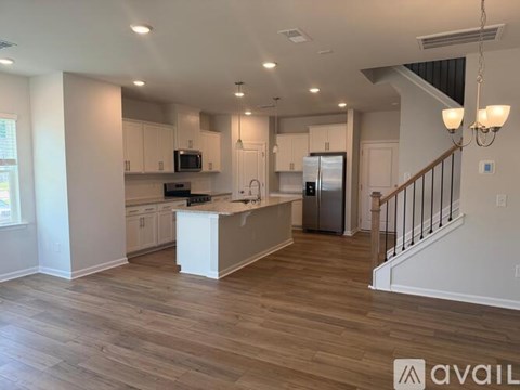 A spacious kitchen with wooden floors and white cabinets.