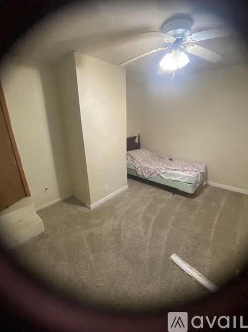A bedroom with a bed, carpet, and a ceiling fan.