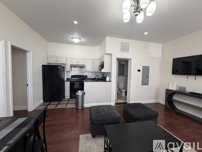A kitchen with a black fridge and a black table with a white logo on it.