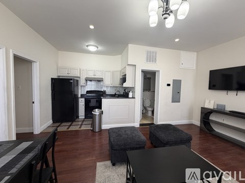 A kitchen with a black fridge and a black table with a white logo on it.