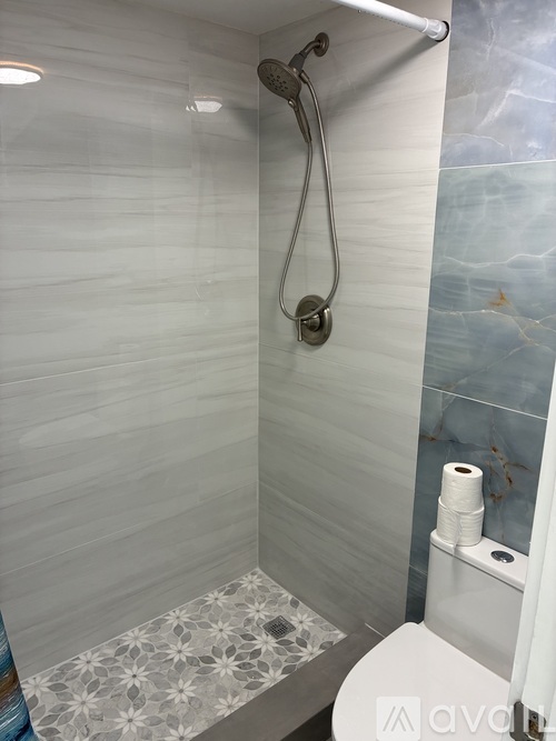 A bathroom with a toilet, a shower, and a tiled floor.