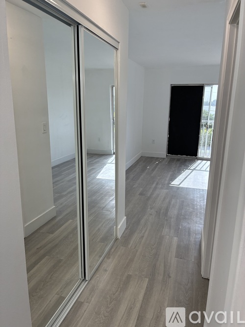 A room with a sliding glass door and wood flooring.