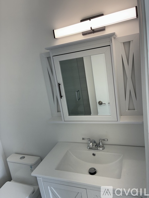 A white bathroom with a sink, toilet and mirror.