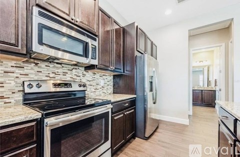A kitchen with dark wood cabinets and a stone backsplash.