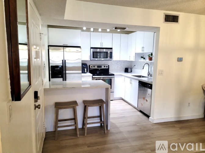 A kitchen with white cabinets and a wooden floor.