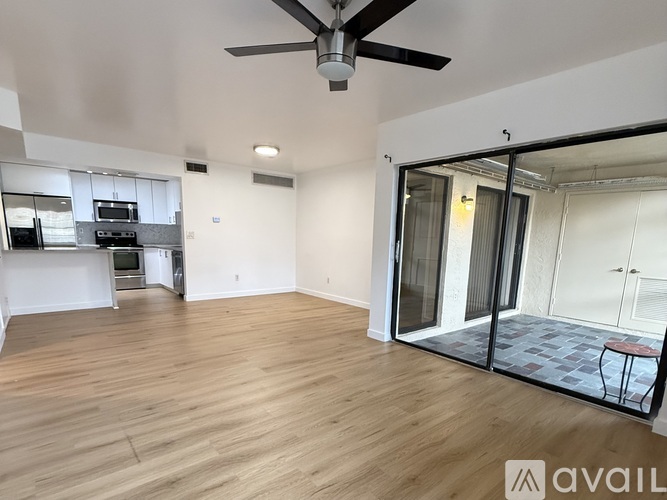 A spacious room with a ceiling fan and wooden flooring.