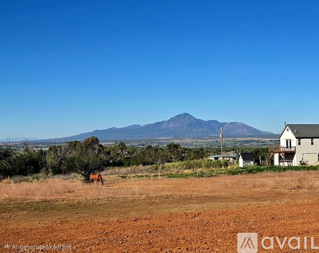 A cow is grazing in a field with a house and mountains in the background.