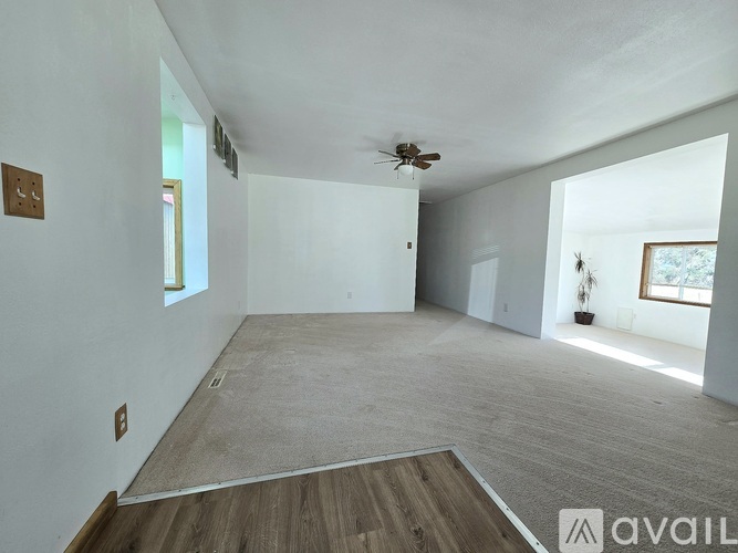 A spacious room with a ceiling fan and a wooden floor.
