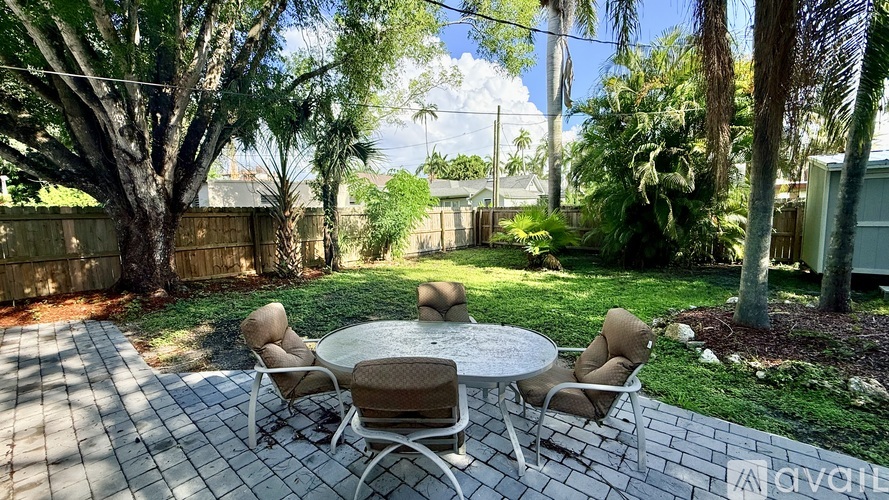 A patio with a table and chairs is surrounded by trees.