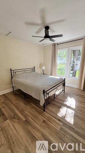 A bedroom with a bed, a ceiling fan, and a sliding glass door.