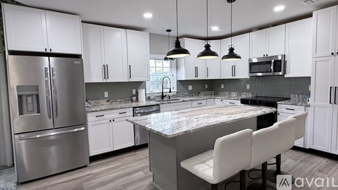A modern kitchen with a marble countertop and stainless steel appliances.