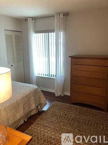 A bedroom with a bed, dresser, and window with curtains.