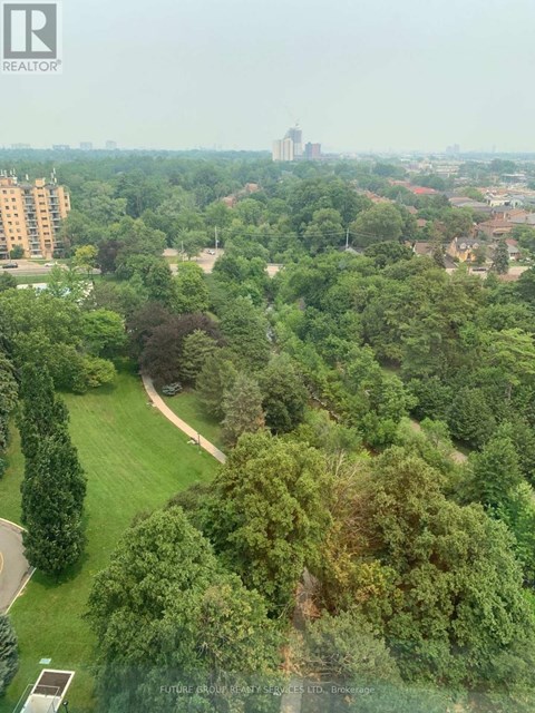 A lush green park with a winding path and apartment buildings in the distance.