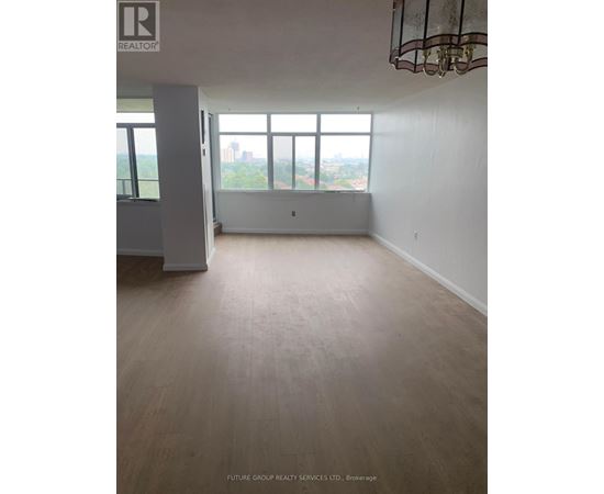 A large empty room with a view of the city through the window.