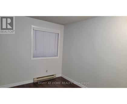 A room with a window and a brokerage sign.